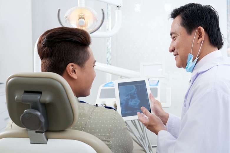 asian-male-dentist-demonstrating-jaw-x-ray-image-tablet-patient
